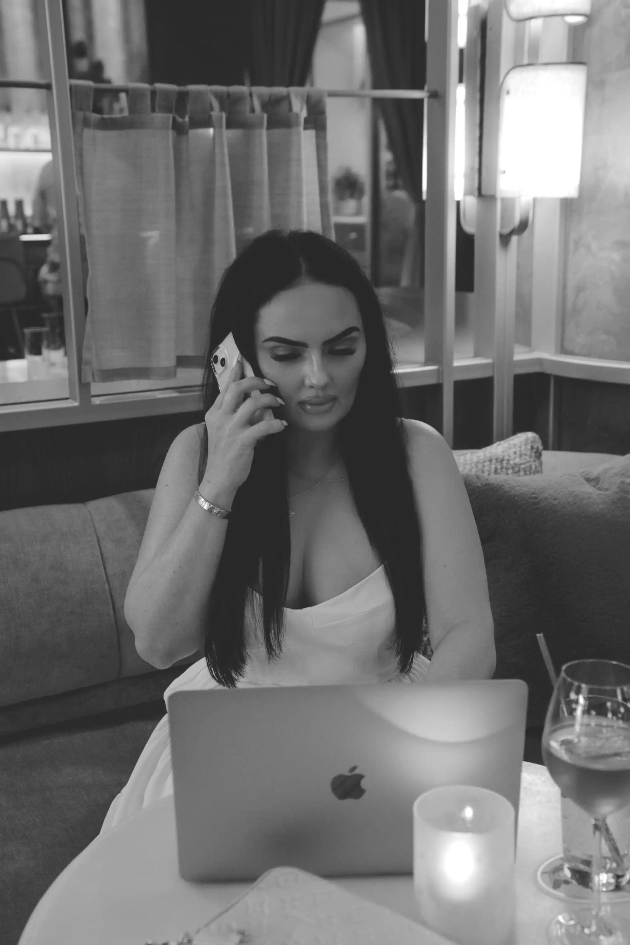 A woman sitting at a table talking on a cell phone.