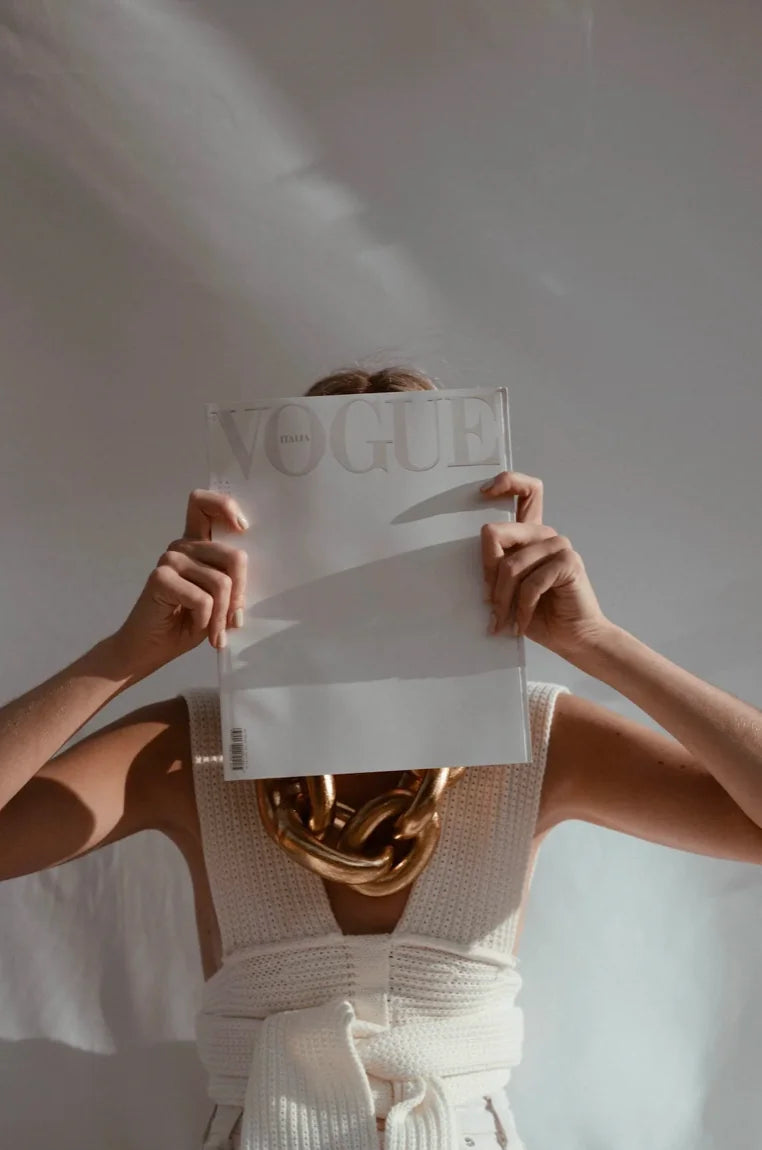 A woman covering her face with a piece of paper.
