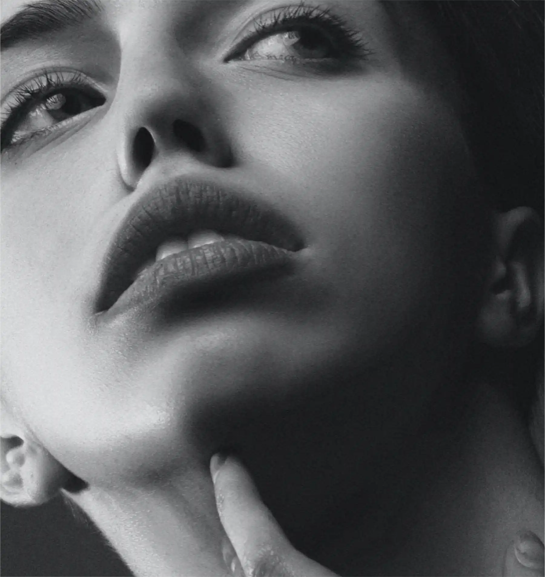 A black and white photo of a woman with her hand on her chin.