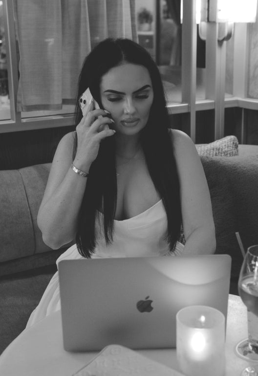 A woman talking on the phone while looking at her laptop