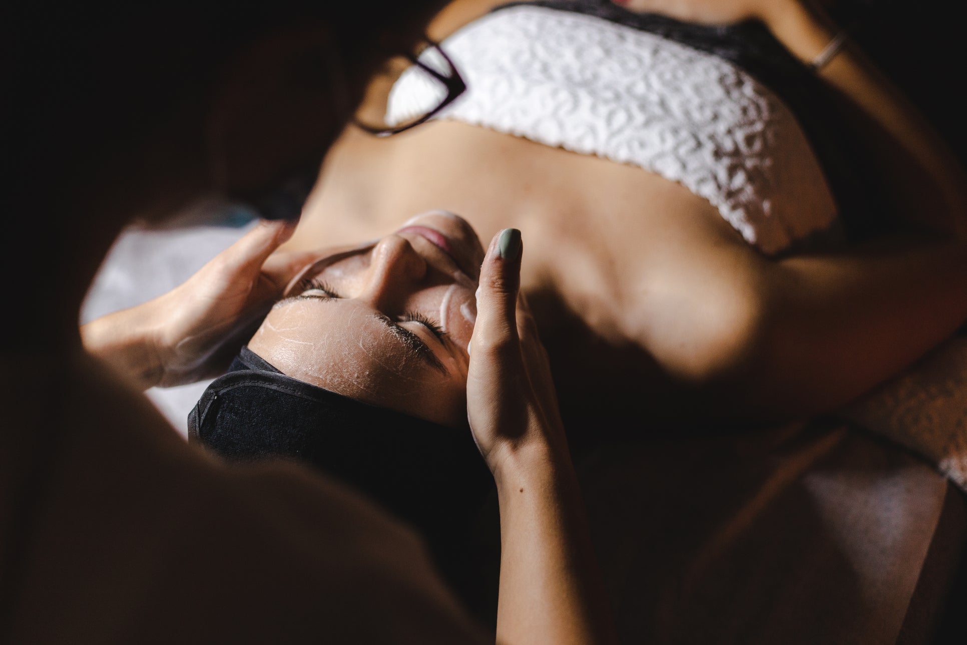 A woman lying down in a towel receiving a facial.