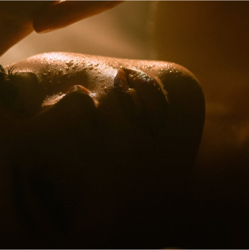 A close up of a woman lying down with water droplets all over her face